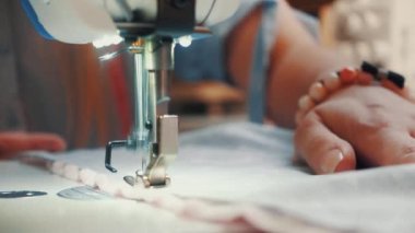 Kadın terzinin atölye masasında otururken makineye dikiş diktiği ekin manzarası