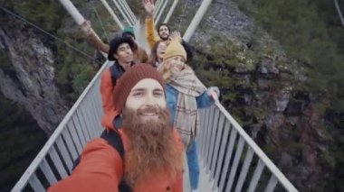 Group of cheerful travelers walking on bridge