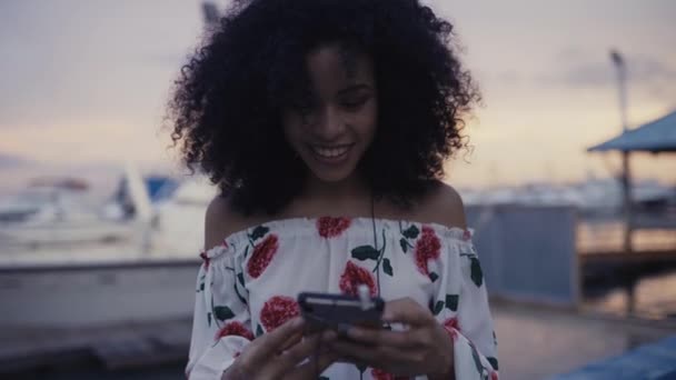 スマートフォンでイヤフォンを持つ笑顔の女性 — ストック動画