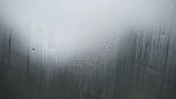 相机倾斜到水滴在蒸腾的窗玻璃上 焦急地奔向阴暗天空下覆盖着雪的岩石 — 图库视频影像