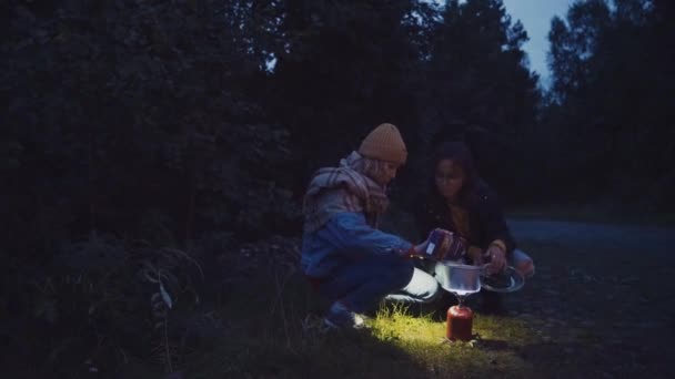 夜の森の中でバーナーで水を加熱する旅行者 — ストック動画