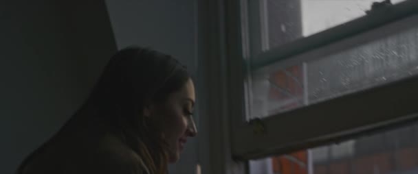 家で窓をあける陽気な女性のバックビューと窓の外に傾いて午前中に街の通りからのぞき見 — ストック動画