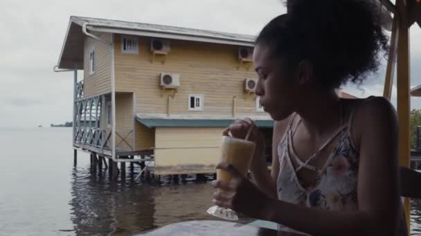 Νεαρή Κυρία Πίνει Μιλκσέικ Κοντά Στο Κτίριο Στο Νερό — Αρχείο Βίντεο