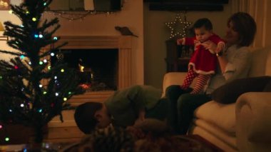 Anne bebekle oynarken, oğul Noel ağacı süslüyordu.