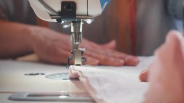 Kadın terzinin atölye masasında otururken makineye dikiş diktiği ekin manzarası