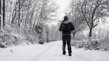 Karlı yolda yürüyen isimsiz bir adam.
