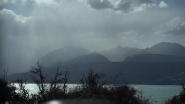 Deniz boyunca sisli ufku olan manzaralı dağ siluetleri.