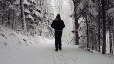 Karlı yolda yürüyen isimsiz bir adam.