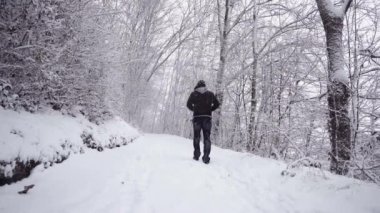 Karlı yolda yürüyen isimsiz bir adam.