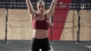 Sporcu kadın spor salonunda ağırlık kaldırıyor.