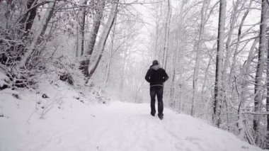 Karlı yolda yürüyen isimsiz bir adam.