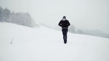 Karlı yolda yürüyen isimsiz bir adam.