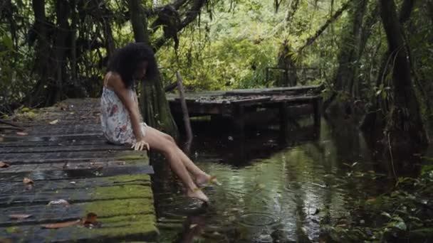 在水边的人行天桥上穿衣的年轻女士 — 图库视频影像