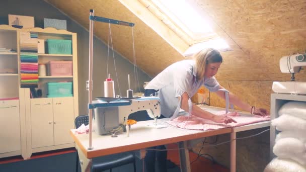 Vrouwelijke Kleermaker Onderzoekt Roze Stof Terwijl Naast Tafel Staat Met — Stockvideo