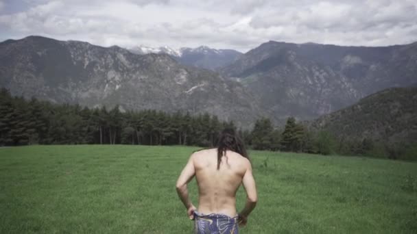 裸の胴が岩によって牧草地を走っている男性 — ストック動画