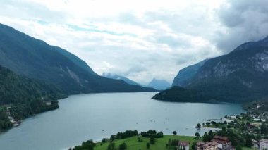 Molveno Gölü 'nün nefes kesici panoramik manzarası Dolomitler, İtalya' da. Görkemli dağlar ve yemyeşil bulutlu bir gökyüzünün altında huzurlu ve resim gibi bir ortam yaratır..