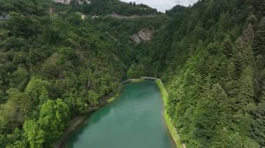 Molveno, Dolomites, İtalya 'nın yemyeşil ormanlarında yuva yapmış pitoresk bir göl. Huzurlu su, zengin bitki örtüsüyle çelişiyor ve doğada huzurlu bir kaçış sunuyor..