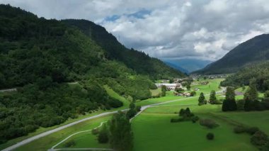 İtalya 'nın Dolomites kentindeki Molveno' nun görkemli manzarasında yemyeşil tepeler, dolambaçlı yollar ve dramatik bulutlu gökyüzü altında dağınık evler serin ve huzurlu bir ortam sunuyor..