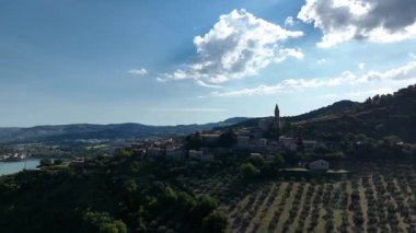 İtalya 'nın kırsal kesimindeki Lago di Polverina' nın sakin manzarası, engin mavi gökyüzü altında dağınık bulutlarla doğa ve mimarinin ahenkli bir karışımını sergiliyor..