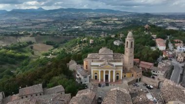 Marche, İtalya 'daki Pollenza' nın hava görüntüsü, tarihi mimarinin ve bulutlu bir gökyüzü altında genişleyen kırsal manzaraların çarpıcı bir karışımını sergiliyor..