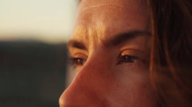 Close-up of a woman's eyes reflecting the warm colors of the sunset in Gran Canaria, Spain, capturing a moment of tranquility and connection with the beauty of nature.