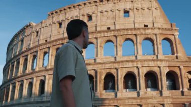 Bir gezgin, açık bir gökyüzünün altında İtalya, Roma 'daki görkemli Colosseum' a bakıyor. Antik amfitiyatro, Roma mühendisliği ve kültürünün bir kanıtı olarak duruyor..