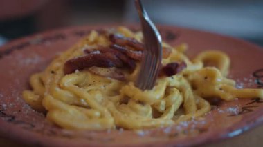 Geleneksel İtalyan carbonara makarna tabağında servis edilen, üzerinde çıtır pancetta ve taze rendelenmiş peynir bulunan, Roma mutfağının özünü yakalayan,.
