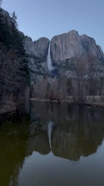 Yosemite Düşük Şelalesi 'nin sakin sudaki yansımasıyla sakin bir görüntüsü. Alacakaranlık ışığı, doğal güzelliği artırmak için sakin bir atmosfer ekler..