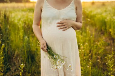 Tanımlanamayan hamile bir kadın güneşli bir tarlada huzur ve mutluluk saçarak geziniyor. Eli karnına hafifçe dayanıyor. Aşkı ve beklentiyi simgeliyor..