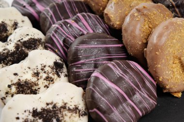 Kalp şeklinde donutlar çikolata, pembe ve krema kaplı malzemeler sergiliyor.