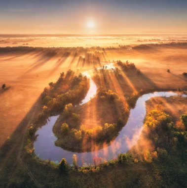 Ukrayna 'da sonbaharda gündoğumunda alçak bulutlarda güzel kıvrımlı nehrin hava manzarası. Nehir kıvrımları, çayırlar ve tarlalar, çimenler, portakal ağaçları, sonbaharda şafakta altın güneş ışınları. Nehir kıyısının en üst manzarası