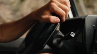 Direksiyona tutunan, Madeira 'nın resimli ve dolambaçlı yollarında gezinen, arabayla seyahat ve macerayı vurgulayan bir kişinin yakın çekimi