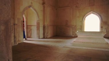 Bir kadın, mimari ve kültür mirasını sergileyerek bir Hint tapınağının antik iç kısımlarında yürüyor. Yumuşak ışık kemerli pencerelerden süzülerek sakin bir atmosfer yaratır..