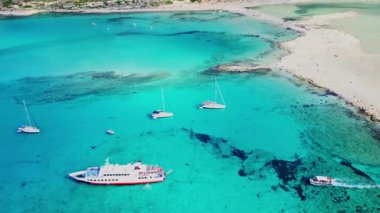 Yunanistan 'ın Girit kentindeki Balos Sahili' nin canlı turkuaz sularını çarpıcı bir hava manzarası yakalıyor. Birkaç tekne berrak sulara demir atmış, sakin bir manzara sergiliyorlar..