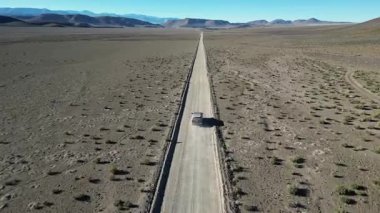 Arjantin, La Puna 'da ücra bir çöl yolunda yalnız bir araç seyahat ediyor. Geniş düzlükleri ve uzak dağlarıyla geniş arazi dramatik ve sakin bir manzara yaratır..