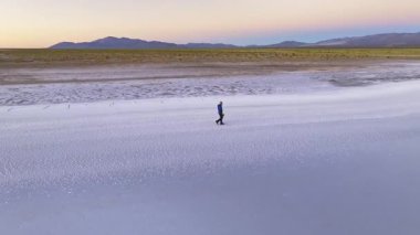 Salinas Grandes, Salta, Arjantin 'in uçsuz bucaksız, sakin tuz düzlüklerinde tek başına yürüyen bir adam. Geniş manzara, sakin güzelliği ve bölgenin eşsiz manzarasını yakalıyor..