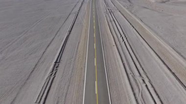 Arjantin 'deki La Puna' nın çöl manzarasından geçen ıssız bir yolun havadan görünüşü. Video, uzak ve yüksek rakımlı bir ortamın saf güzelliğini yakalıyor..