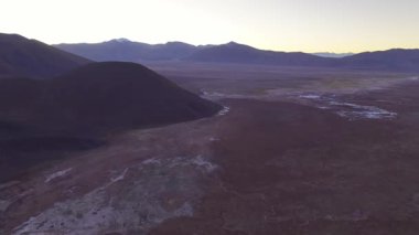 Gün doğumunda La Puna, Salta, Arjantin 'deki Salar de Pocitos' un engin çöl manzarası. Çorak arazi, sabahın erken saatlerindeki gökyüzü ile çelişiyor ve uzak güzelliğini vurguluyor..