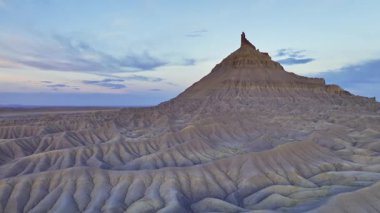 Fabrika Butte, engin Utah çölüne karşı belirgin bir şekilde duruyor, alacakaranlıkta berrak mavi bir gökyüzünün altında aşınmış kalçalar ve çıkıntılar sergiliyor..