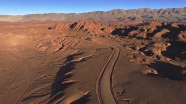 Arjantin, La Puna 'nın çarpıcı kurak arazisinde dolambaçlı bir yol uzanır. Görkemli dağlara bakan bu uzak çöl manzarası bölgenin engebeli güzelliğini yakalıyor..