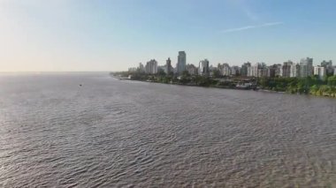 Rosario, Arjantin 'in çarpıcı panoramik manzarası, açık mavi gökyüzü altında Parana Nehri boyunca modern ufuk çizgisini sergiliyor, kentsel ve doğal güzellikleri harmanlıyor..