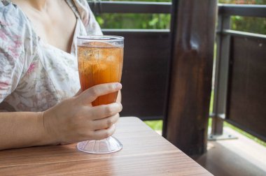 Elinde bir bardak buzlu çay tutan tanınmamış genç kadın.