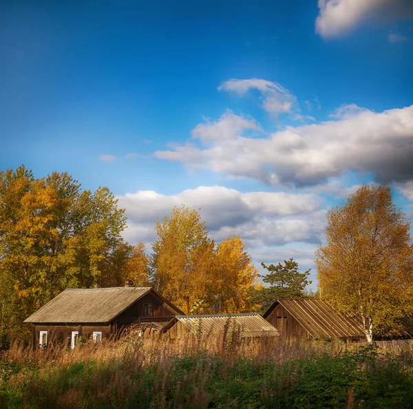 A casa de campo escondido grama alta e árvores. No início do Outono. O céu azul nublado . — Fotografia de Stock