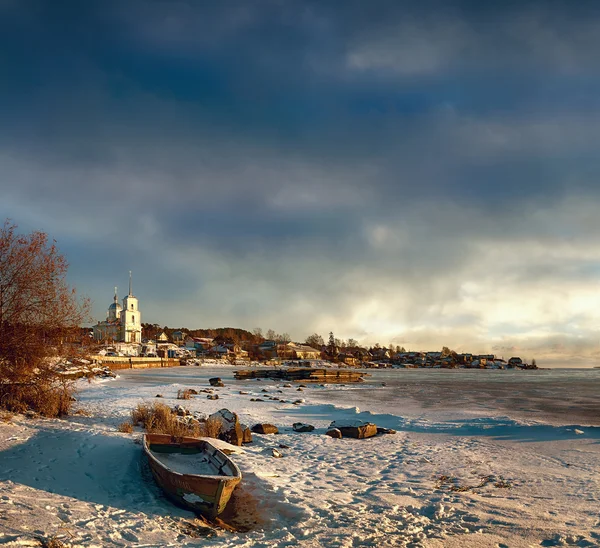 Russia. The Orthodox Church on the shore of a frozen lake. In the foreground an old boat. winter evening. — Stock Image Russia. The Orthodox Church on the shore of a frozen lake. In the foreground an old boat. winter evening. Royalty Free Stock Images