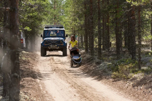 Bir orman yolu üzerinde SUV bir kadın bir bebek arabası ile yakalıyor. Off-road yarış. Girvas 18.07.2015. Yaz, kum.