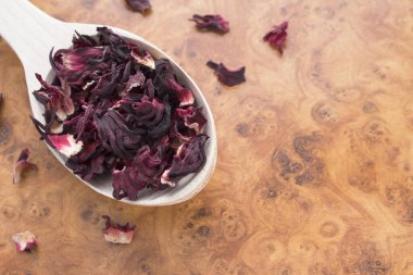 Ahşap arka planda tahta kaşıkta kırmızı çay, üst manzara.