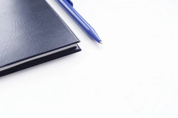 Siyah defter ve mavi kalem beyaz arkaplanda izole edildi