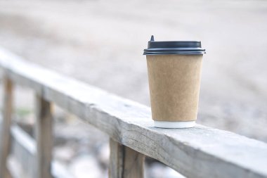 Yakın plan kağıt bardak kahve, arka planda, ahşap korkulukların üzerinde. Bir kahve dükkanı için.