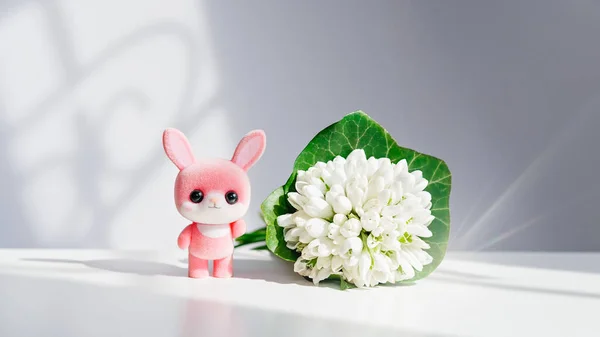 Easter pink bunny, rabbit with spring flowers, a bouquet of snowdrops