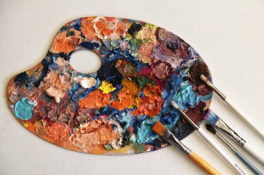 Sanat paletine yakın çekim. Yağlı boyaların parlak noktaları. kullanılmış palet. çok renkli boyalar var. Mesaj için yer var. boya fırçaları